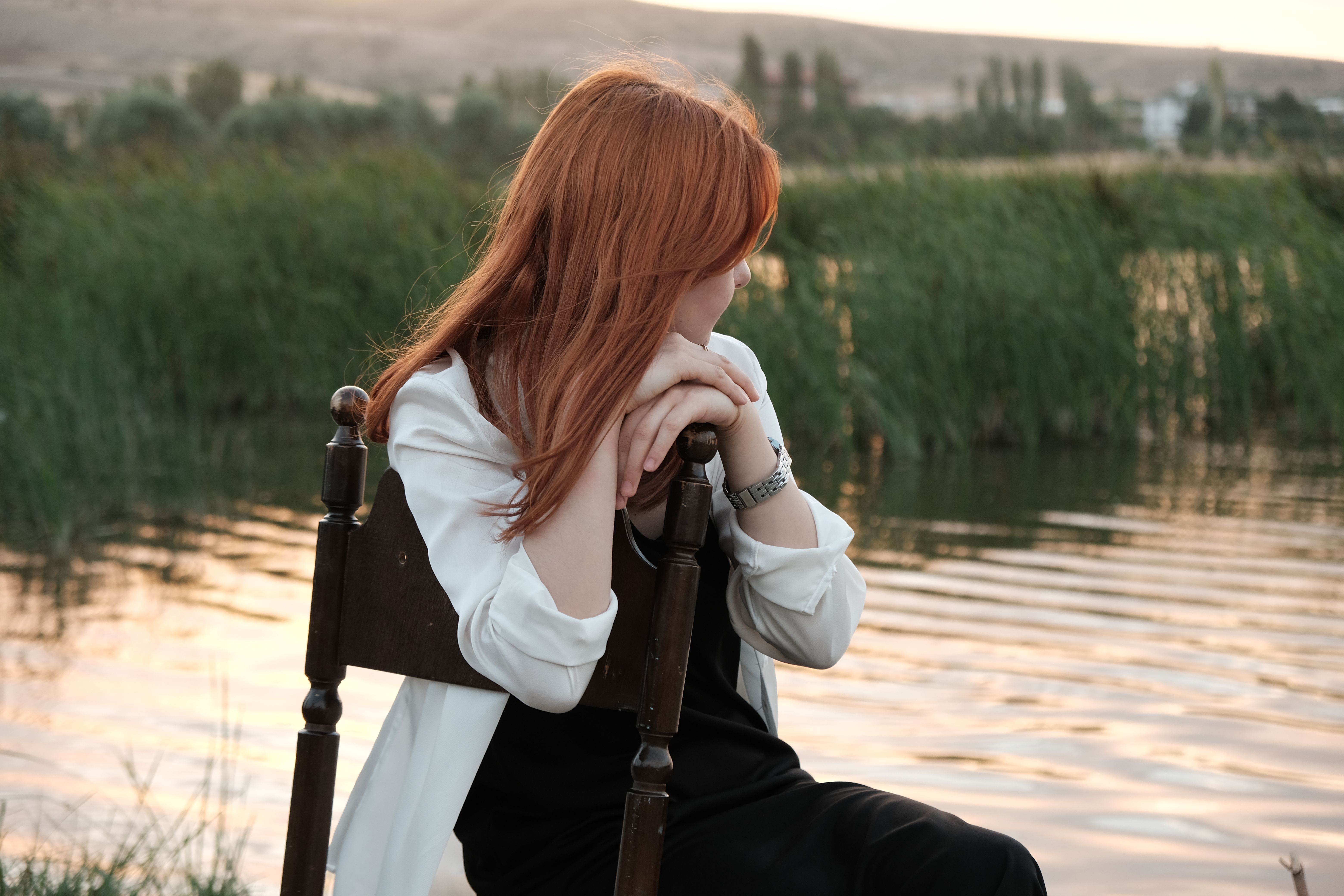 Woman sitting by the lake at sunset, exuding a calm and reflective mood.