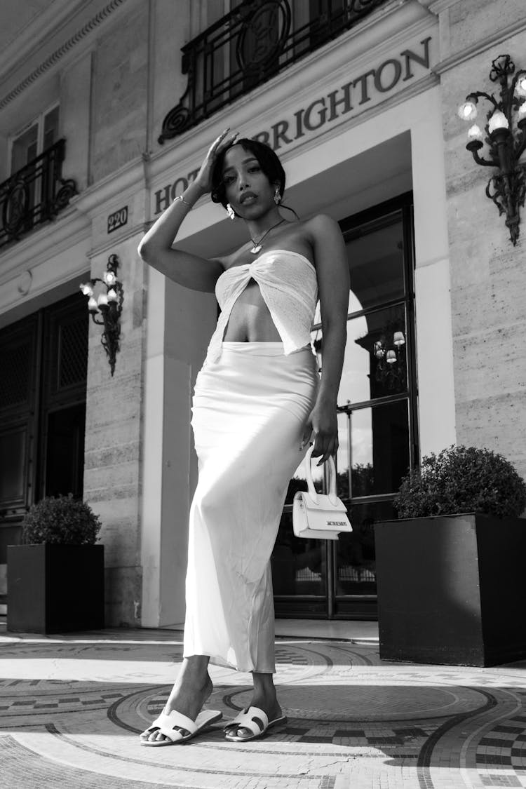 Woman In White Dress Standing By Hotel Entrance