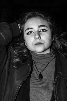 Expressive black and white portrait of a woman in fashion with bold eyeliner and a necklace.