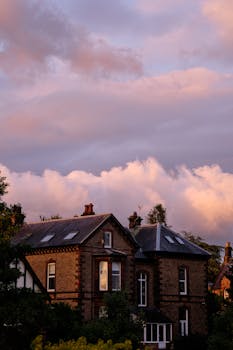 A scenic view of redbrick houses in Penrith, England, silhouetted against a beautiful sunset sky.