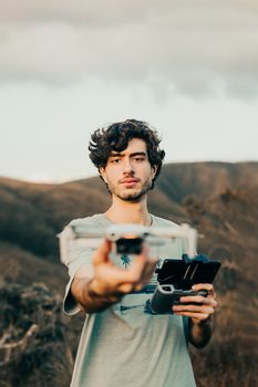 A young man operating a drone in a scenic mountainous landscape, showcasing technology in nature.