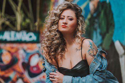 Free Portrait of a fashionable woman in front of a colorful mural, exuding confidence. Stock Photo