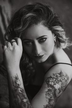 Elegant black and white portrait featuring a tattooed woman with a piercing gaze.