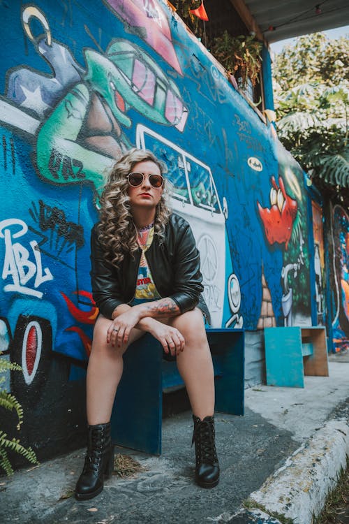 Woman in Jacket Sitting and Posing by Wall with Graffiti