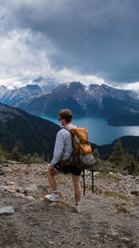 Backpacker overlooking a stunning mountain lake in Garibaldi, BC, Canada during a hike.