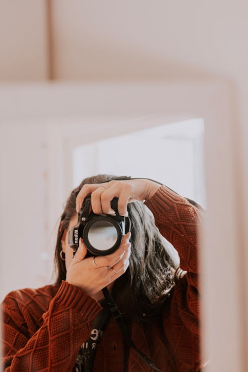 Young Woman Taking a Mirror Selfie with a Camera 