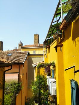 A vibrant yellow alleyway with historic Italian architecture under a clear blue sky.