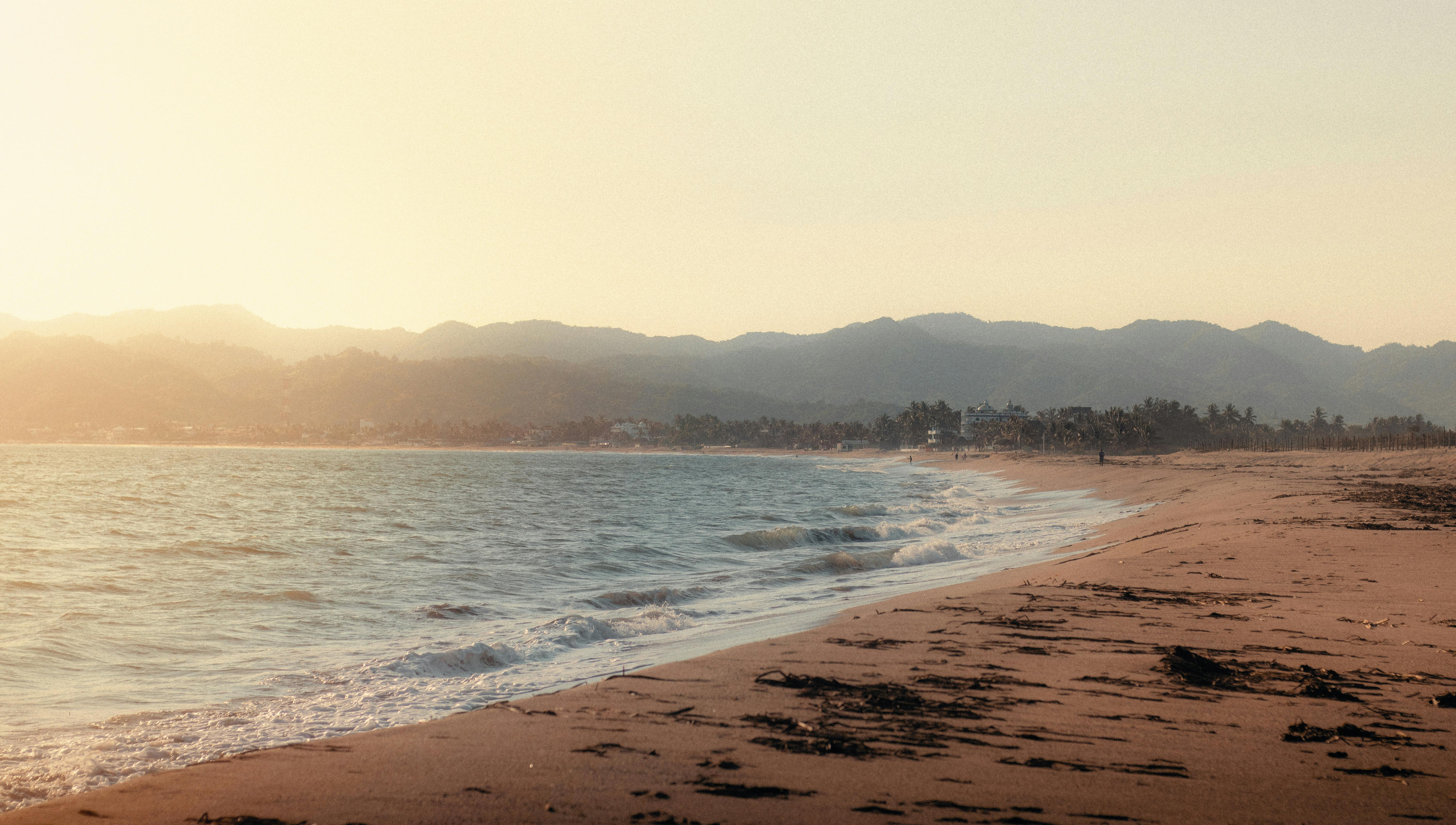 Pacific coast beach at golden sunset with warm orange sky reflecting on calm water