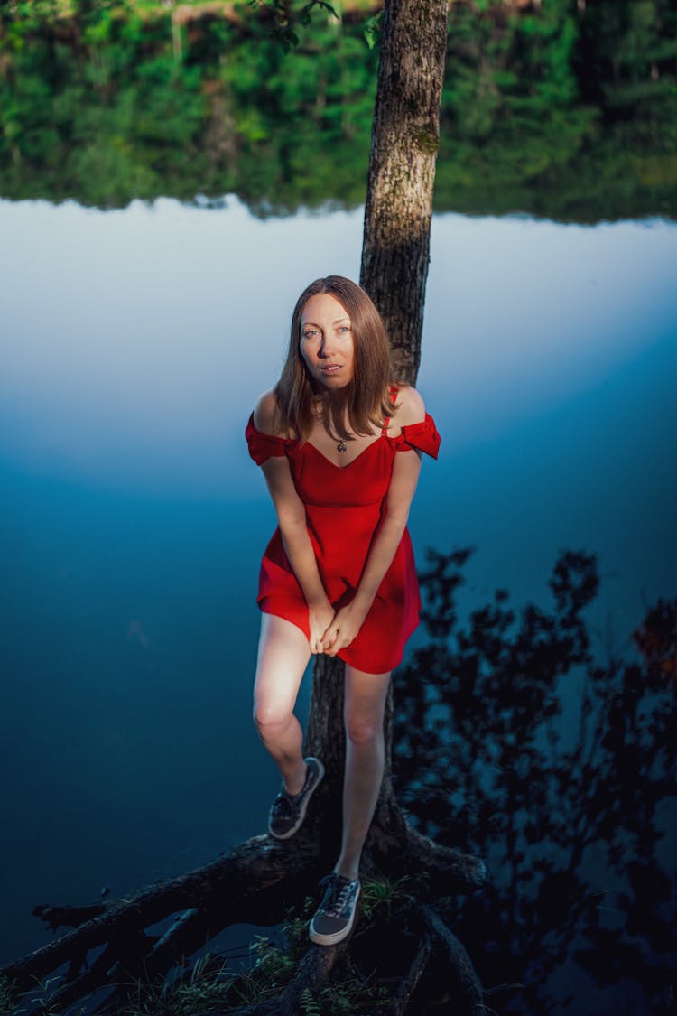 Woman In Red Sundress Standing By Lake