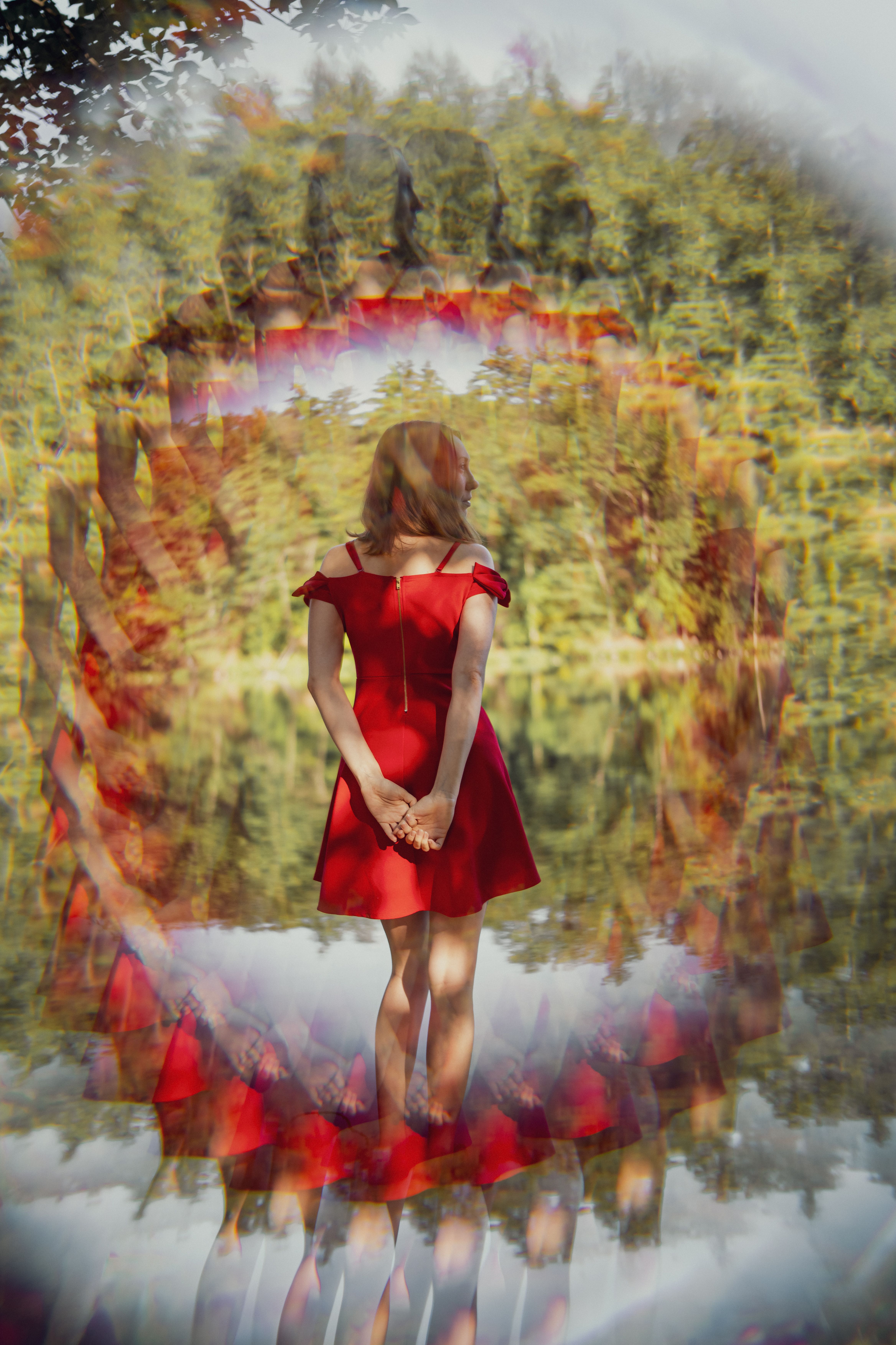 A woman in a red dress stands with hands clasped, surrounded by a dreamy kaleidoscope effect.