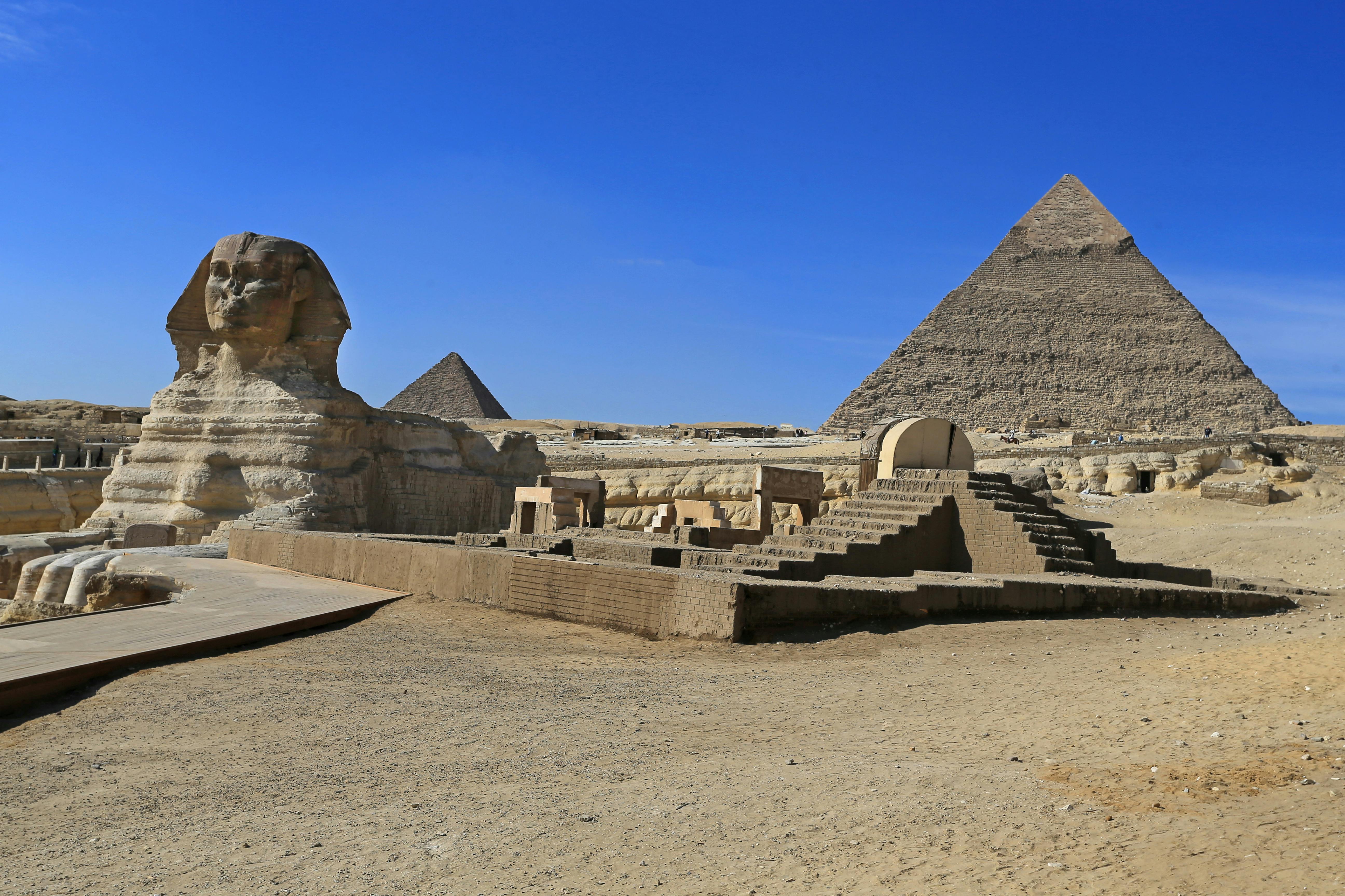 Stunning view of the Great Sphinx and Pyramid of Khafre in Giza, Egypt under clear blue skies.
