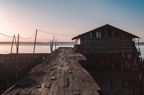 Free A deserted wooden pier extending into the water during a serene sunset. Stock Photo