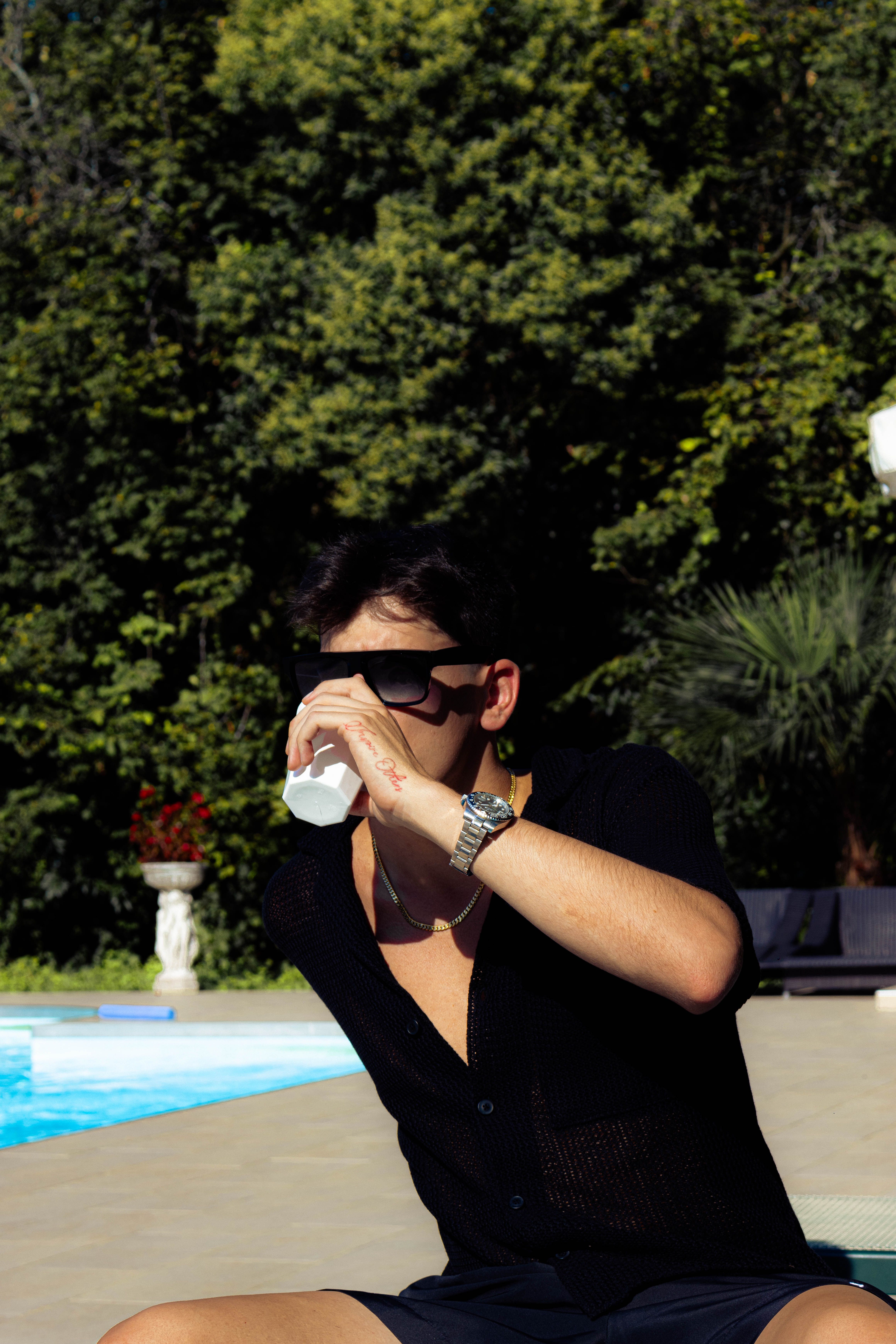 Relaxing vacation scene with man by a pool wearing sunglasses, ideal for travel themes.