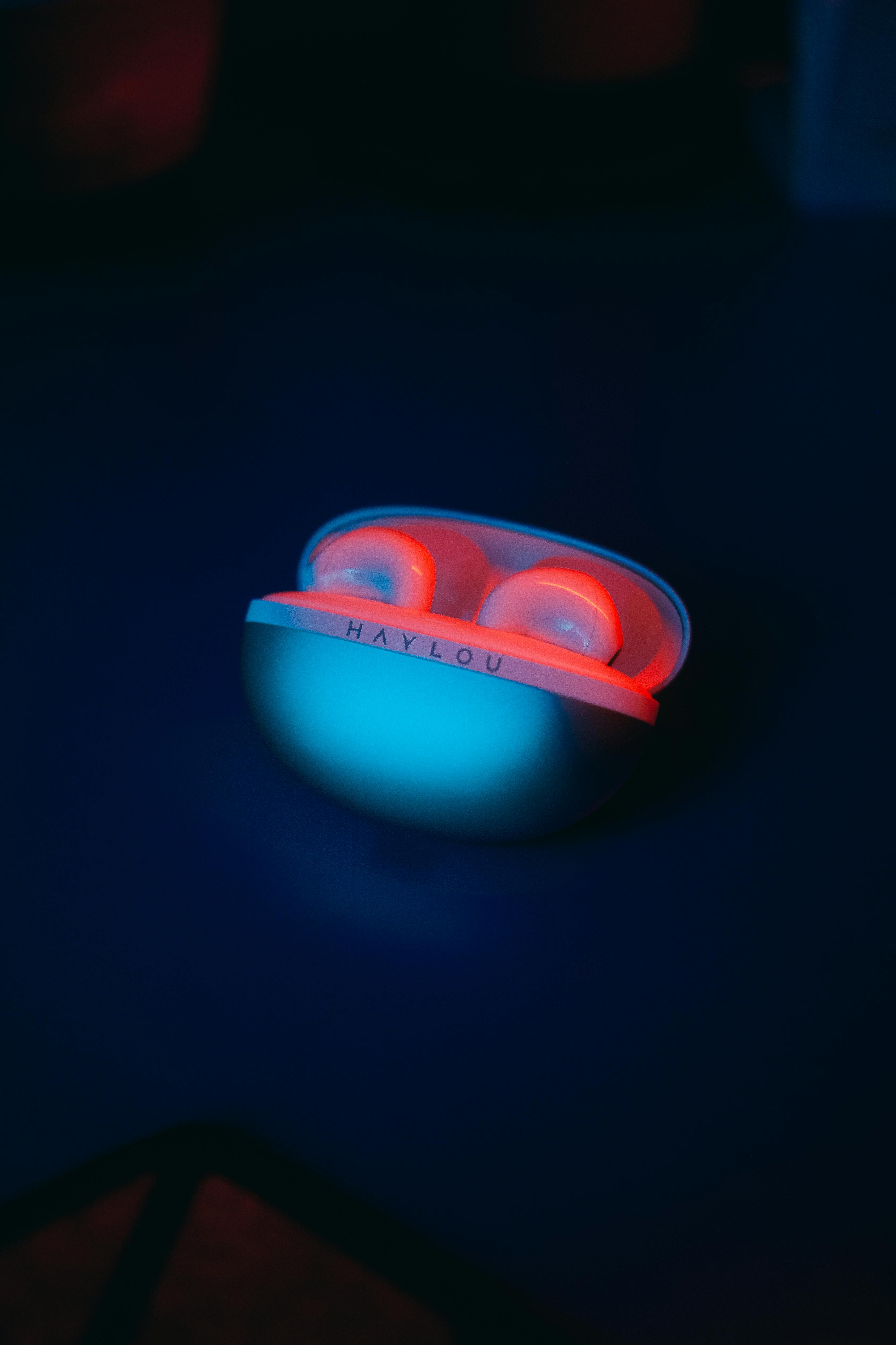 Free Close-up of wireless earphones with glowing red light in a charging case. Stock Photo