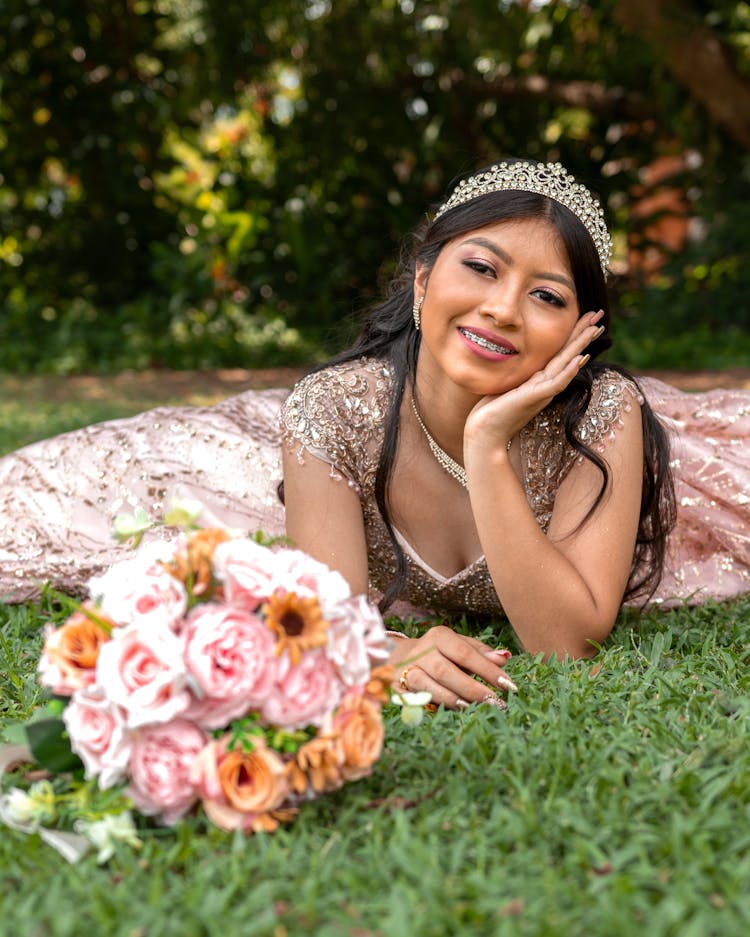 Woman In Dress And Crown Lying Down With Flowers Bouquet