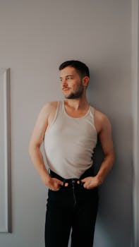 Fashion model standing against a neutral wall in casual attire, exuding confidence and style.