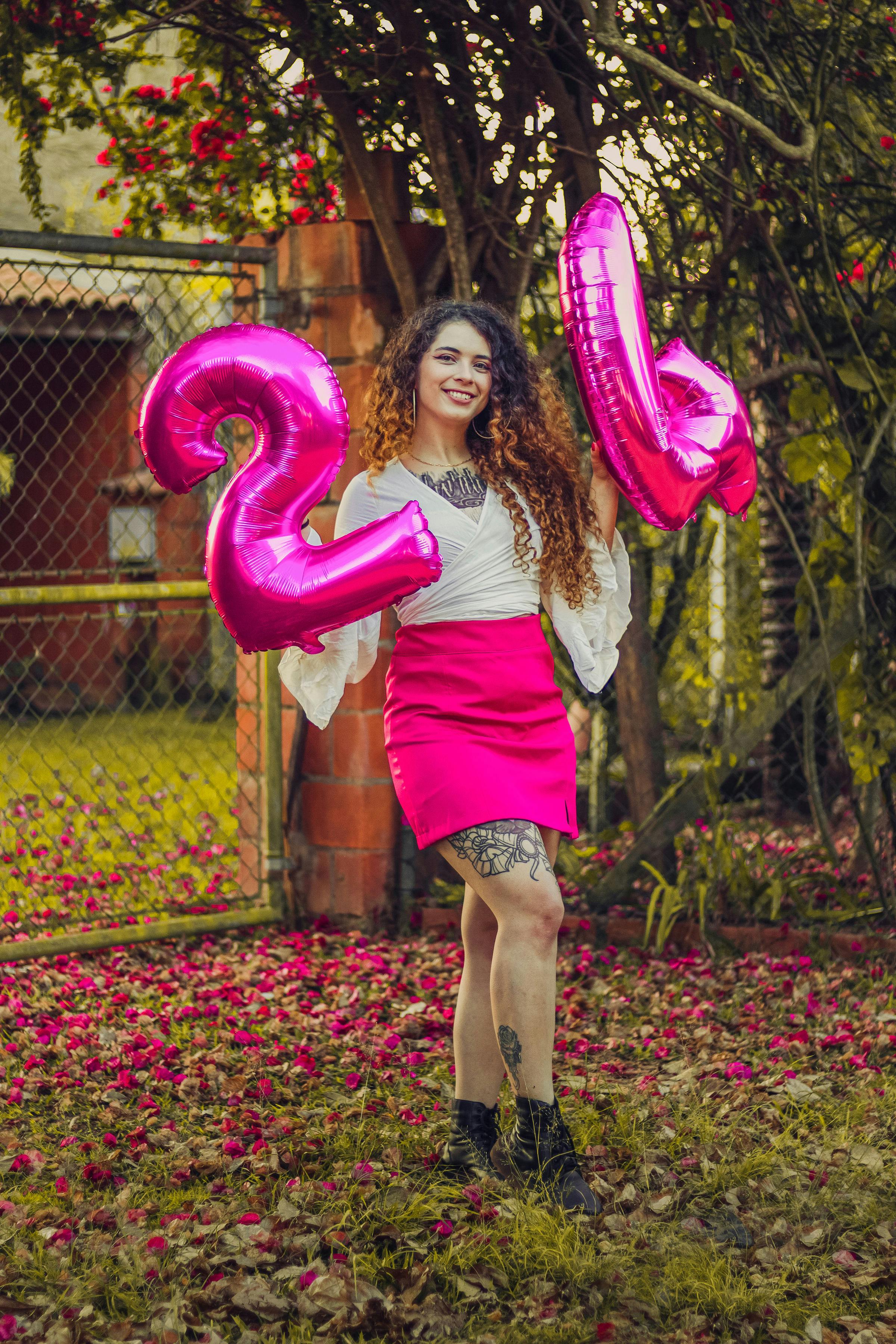 young woman standing outside and holding number balloons