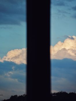 A striking view of clouds framed by a window silhouette against a vibrant sky.