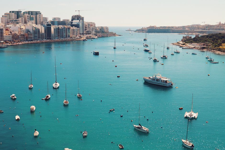 Stunning drone shot of Valletta harbor with sailboats and buildings along the coast of Malta.