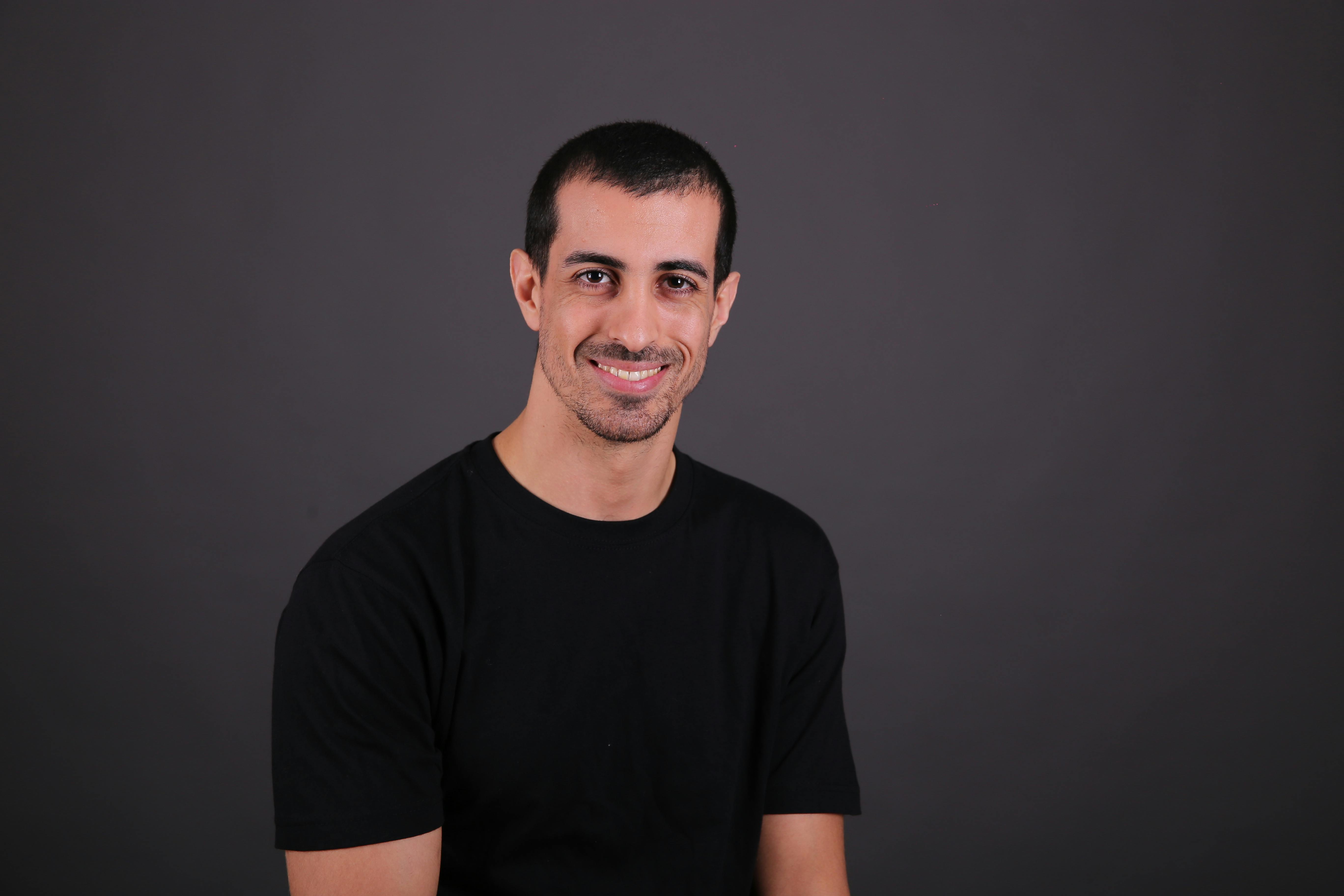 a man in a black shirt smiling for the camera