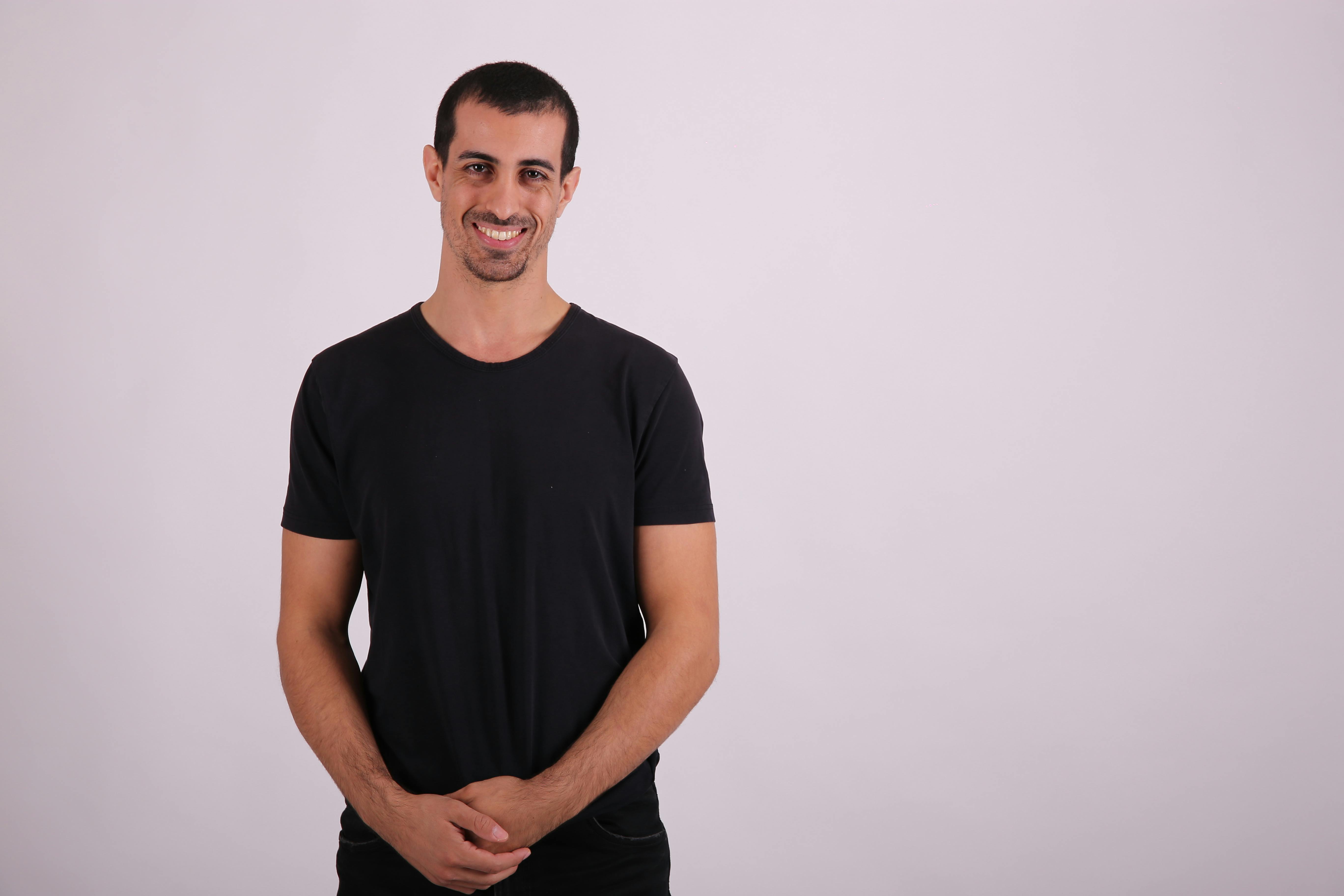 a man in black shirt standing against a white background