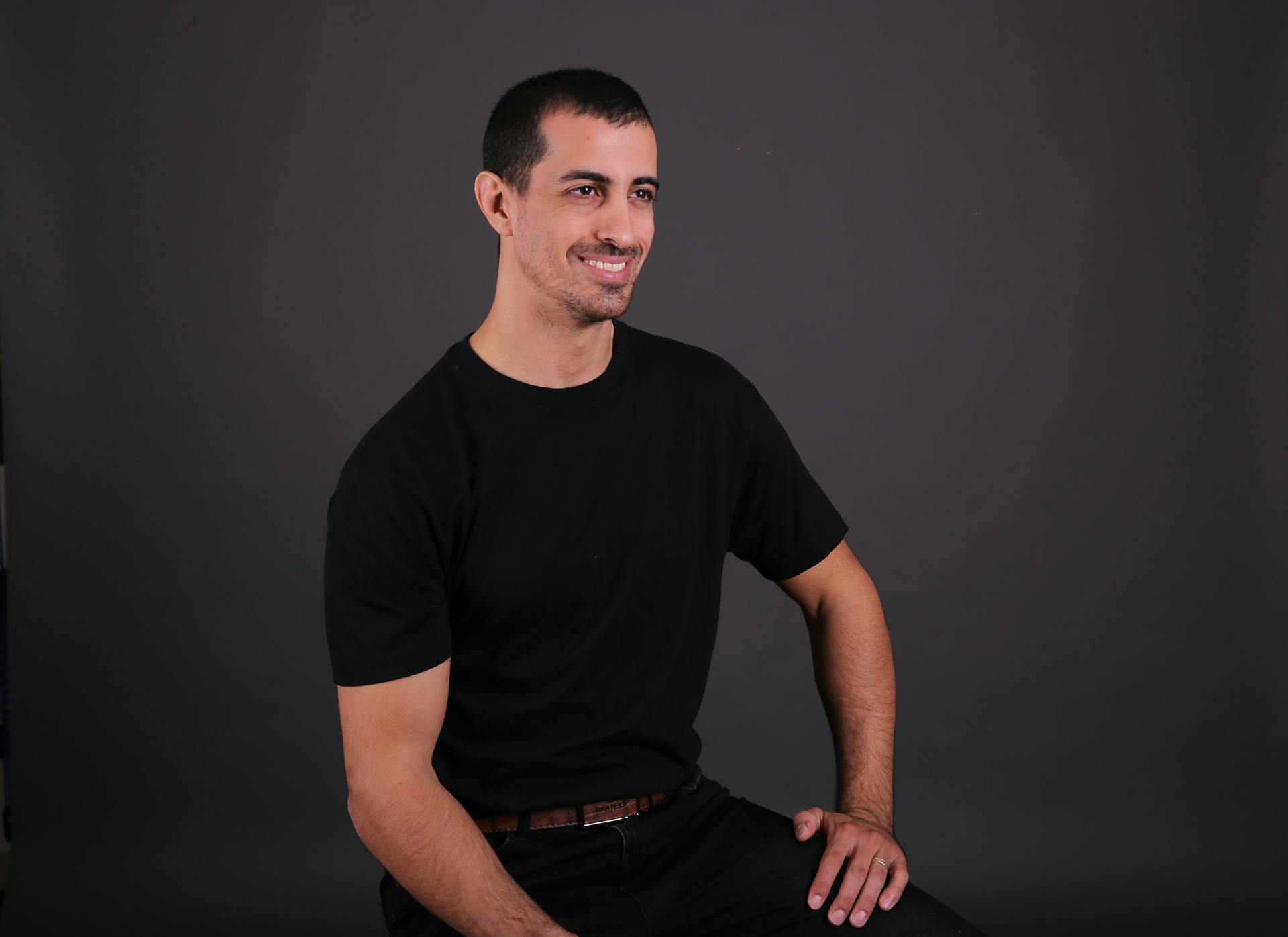 Portrait of a smiling man sitting confidently in a studio setting.