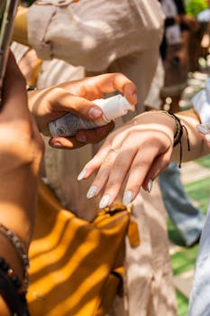 Close-up of two women applying hand cream outdoors during daytime.