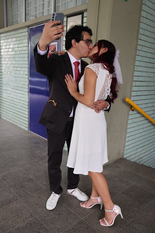 Groom Taking a Picture of Him and the Bride Kissing 