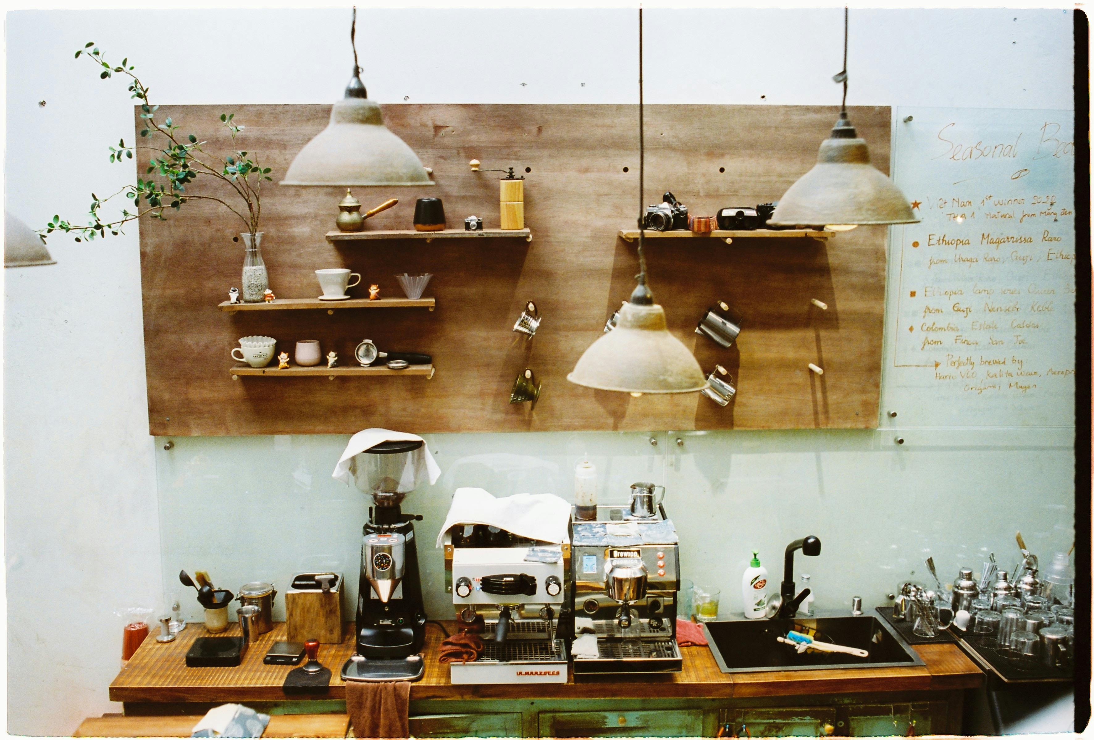 Rustic café interior with coffee machines, grinders, and wooden shelves.