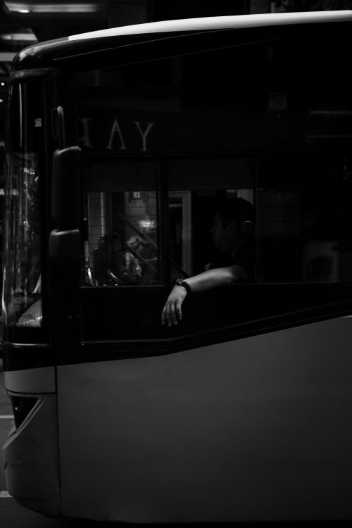 Free A bus driver sits in his seat at nighttime in Ankara, Türkiye, captured in black and white. Stock Photo