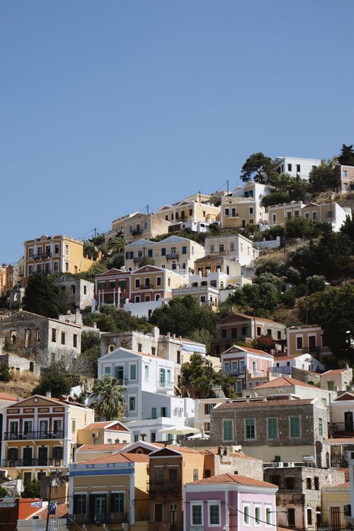 Free Colorful hillside houses in Symi, Greece, under a clear blue sky. Stock Photo