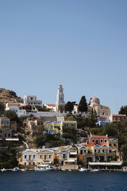 Free Brightly colored buildings on the picturesque harbor of Symi Island, Greece, under clear blue skies. Stock Photo