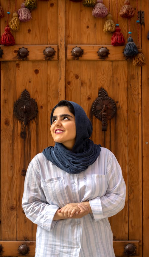 Young Woman Standing in front of Antique Wooden Door and Smiling 