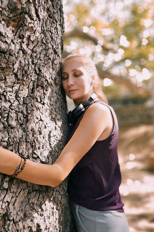 Young Woman in Violet Sleeveless Top Embracing a Tree