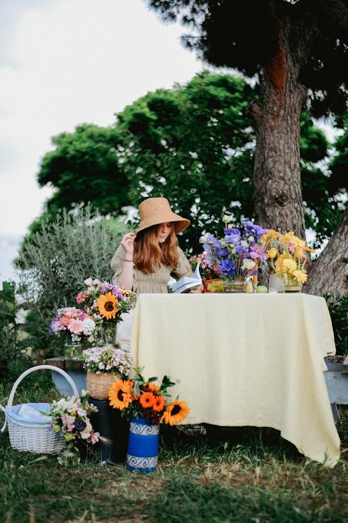 Free A Girl Sitting at the Table in the Garden Decorated with Flowers and Reading a Book Stock Photo