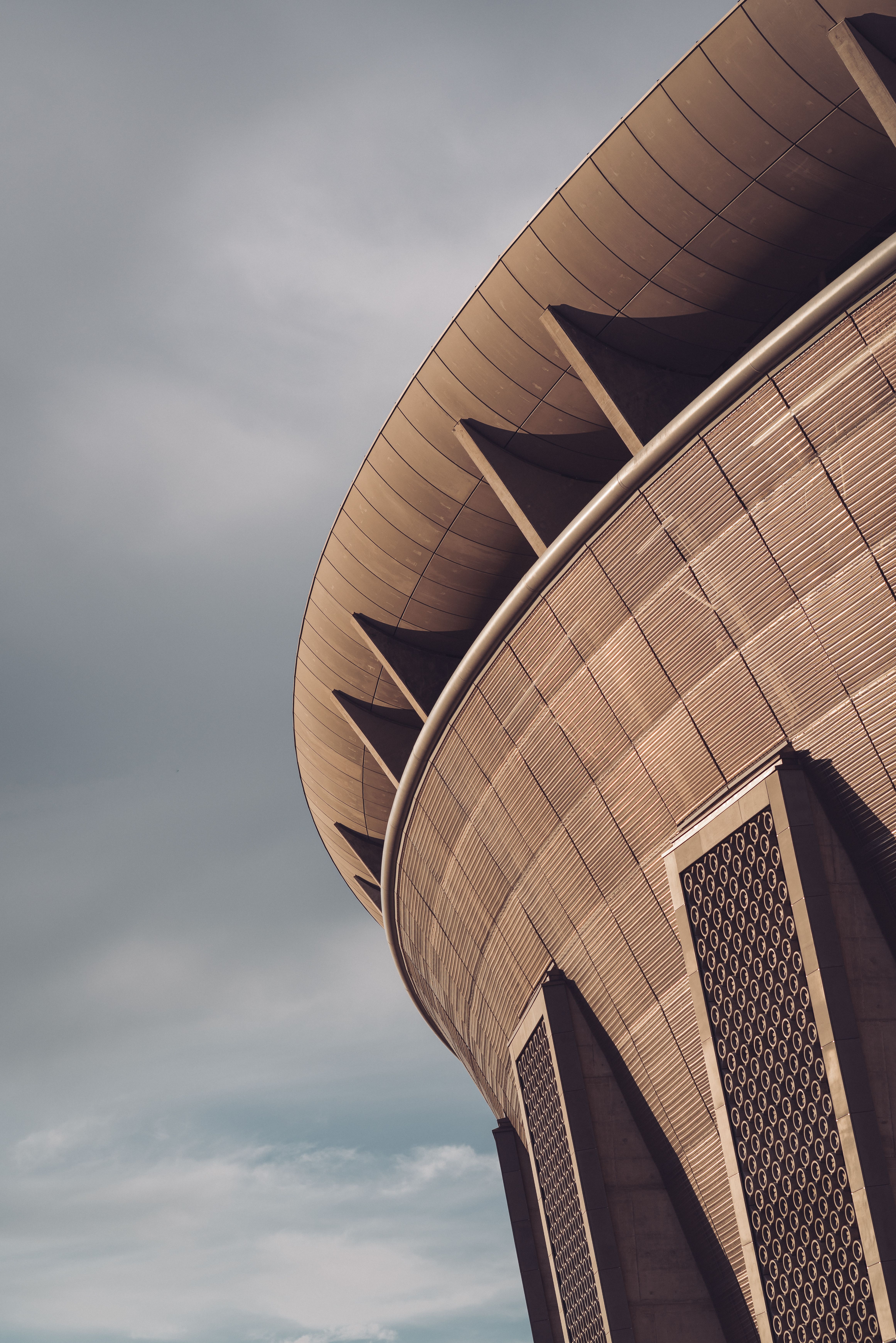 Close-up of Ferenc Puskás Stadium showcasing its modern architecture under a cloudy sky.