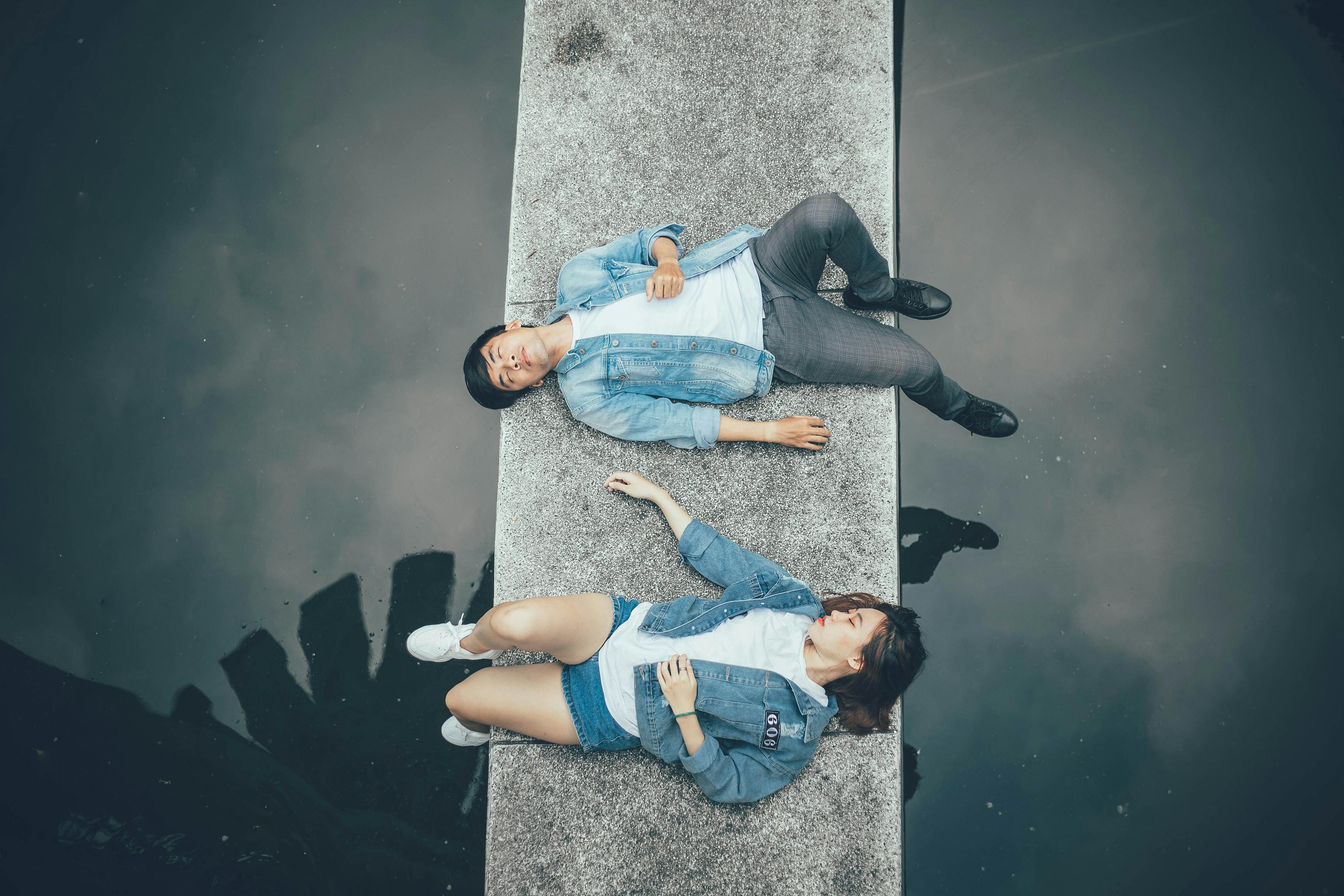 一对夫妇在平静水面的一座桥上放松身心，画面从上方拍摄