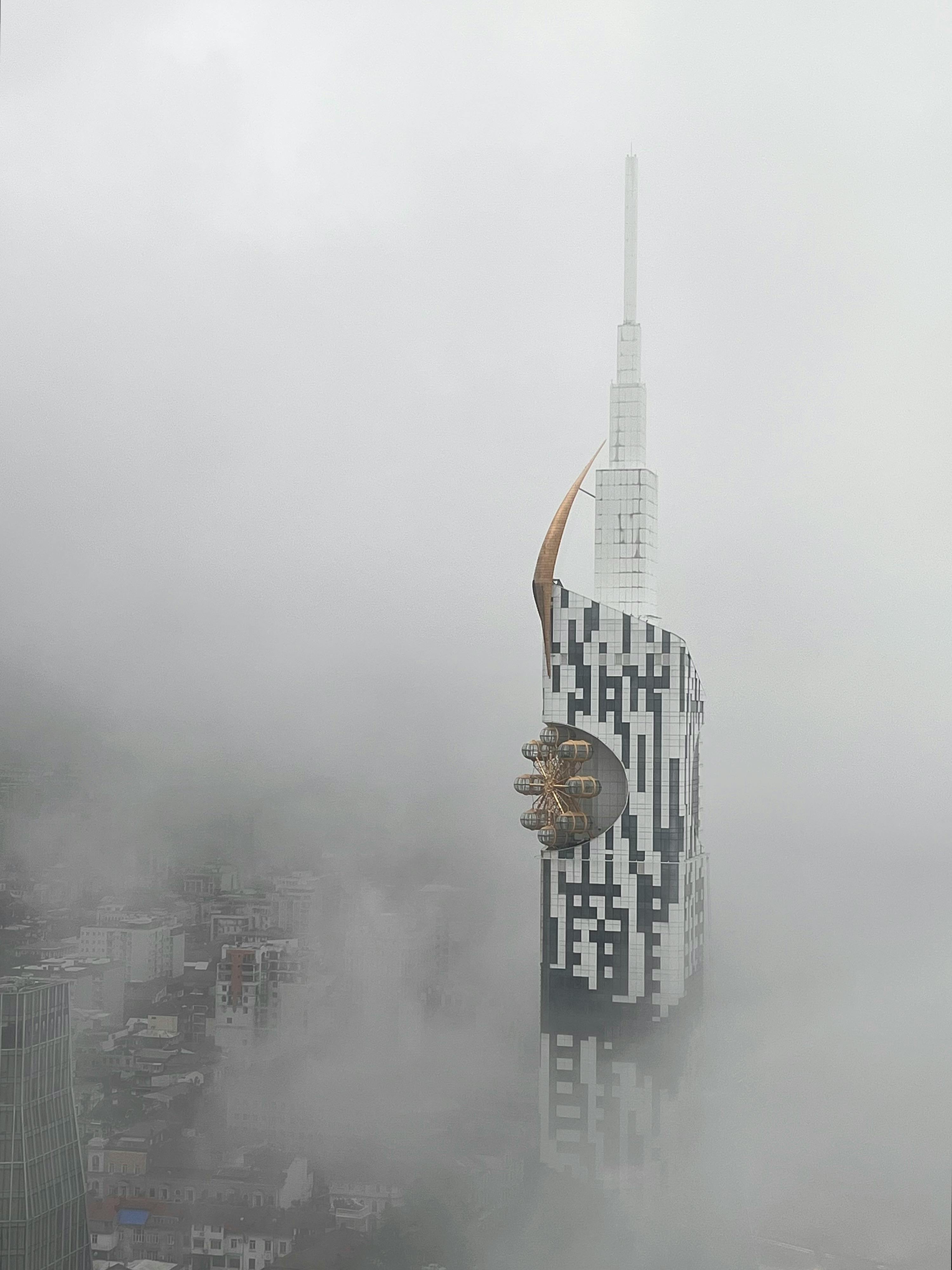 A unique skyscraper in Batumi, Georgia emerges through thick fog, displaying its modern architecture.