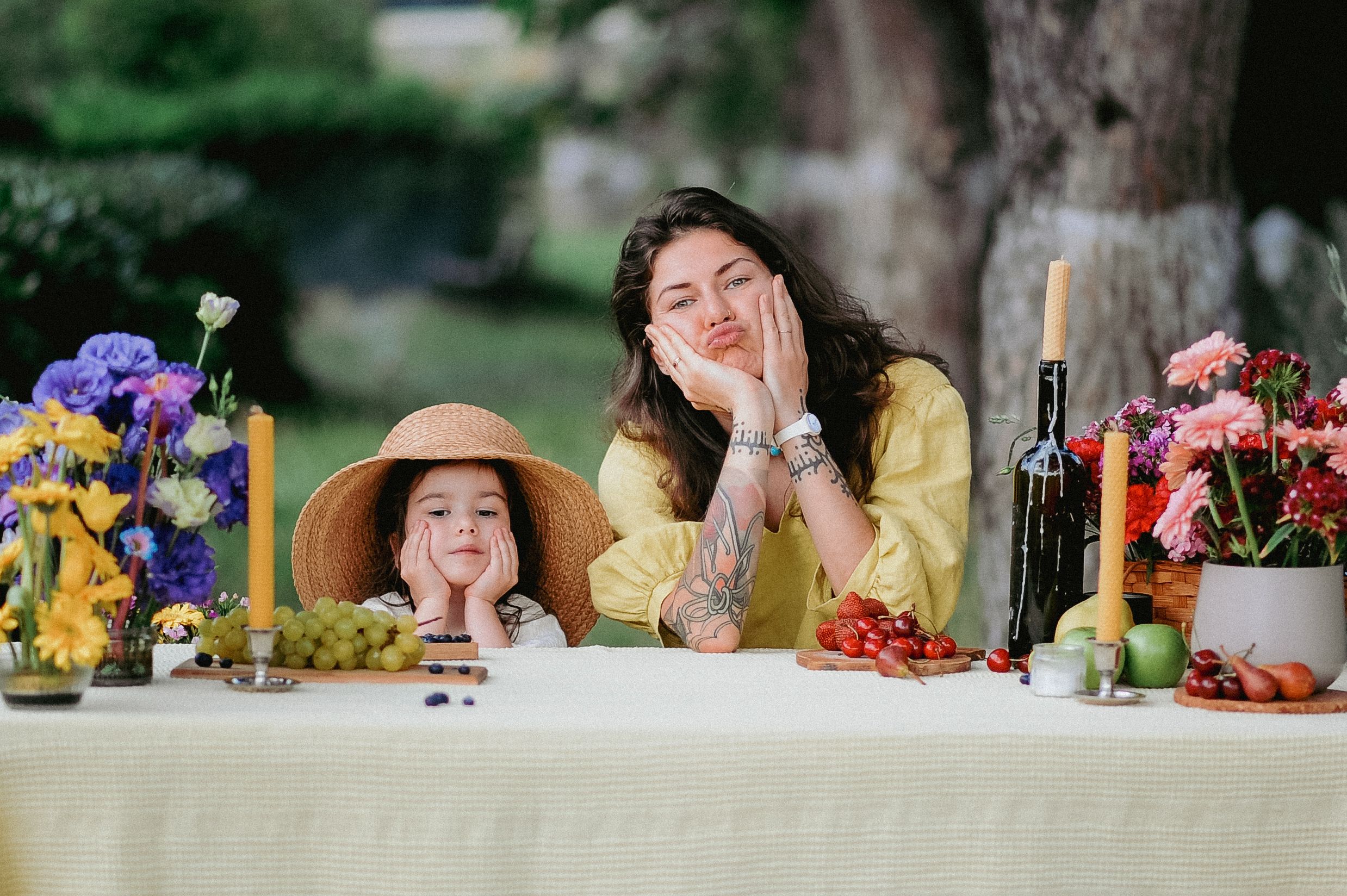 Mother and daughter with a small visible tattoo sharing a playful outdoor picnic moment