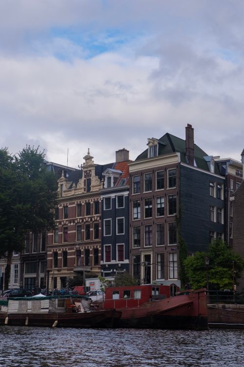 Free Picturesque Amsterdam canal with traditional Dutch architecture and houseboats. Stock Photo