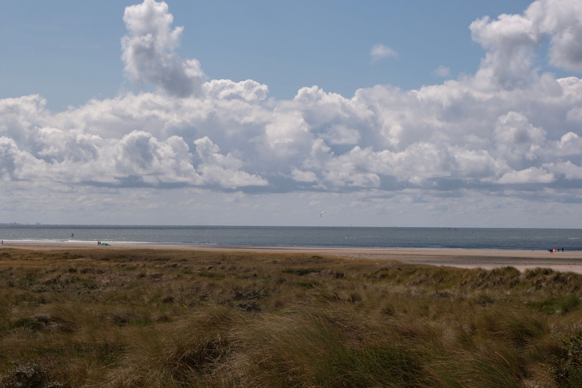 Peaceful beach scene at IJmuiden with dramatic cloud formations and sandy dunes.