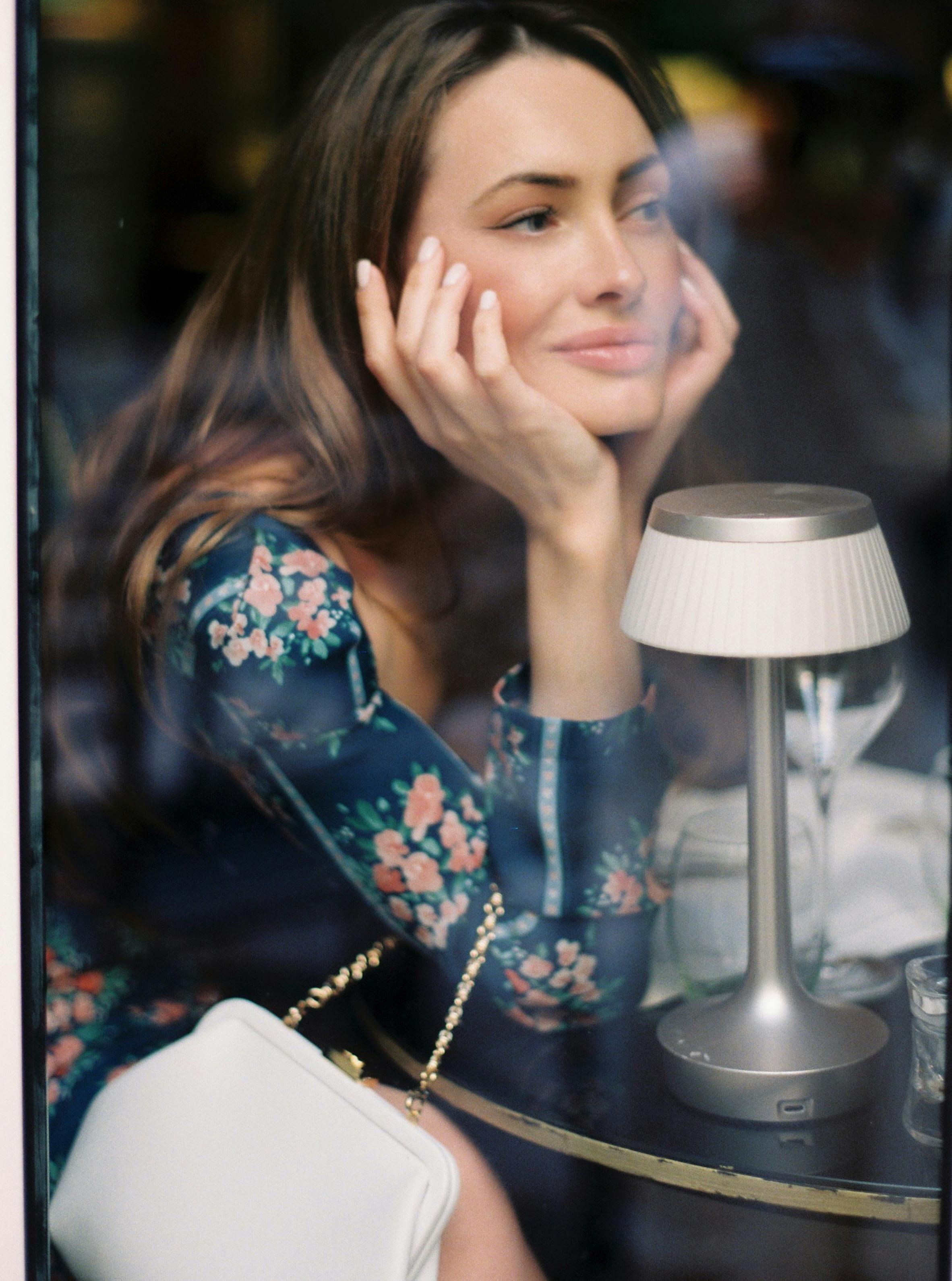 Kostnadsfria Kvinna Som Sitter Vid Bordet Med Händerna På Kinderna Stock foto