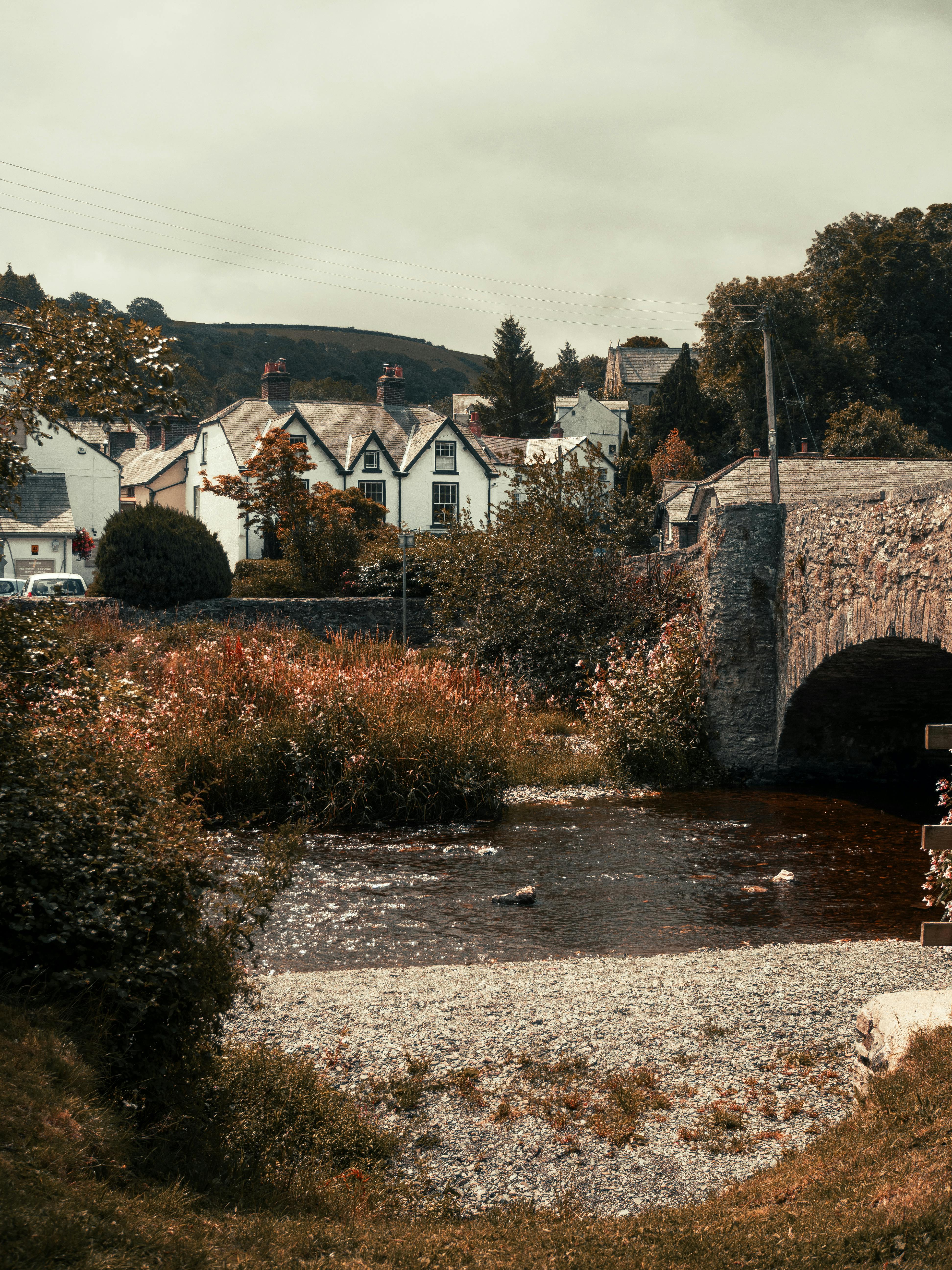Quaint village scene featuring a stone bridge and traditional cottages in Llanfair Talhaiarn, Wales.