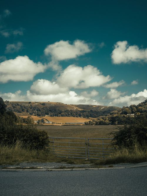 Free Peaceful rural landscape in Llanfair Talhaiarn, Wales showing a serene valley under a vibrant sky. Stock Photo