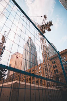 A cityscape featuring skyscrapers, cranes, and urban construction under a clear sky.