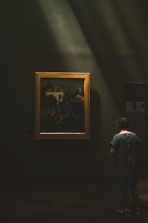 A Woman Standing in an Art Gallery and Looking at a Painting 