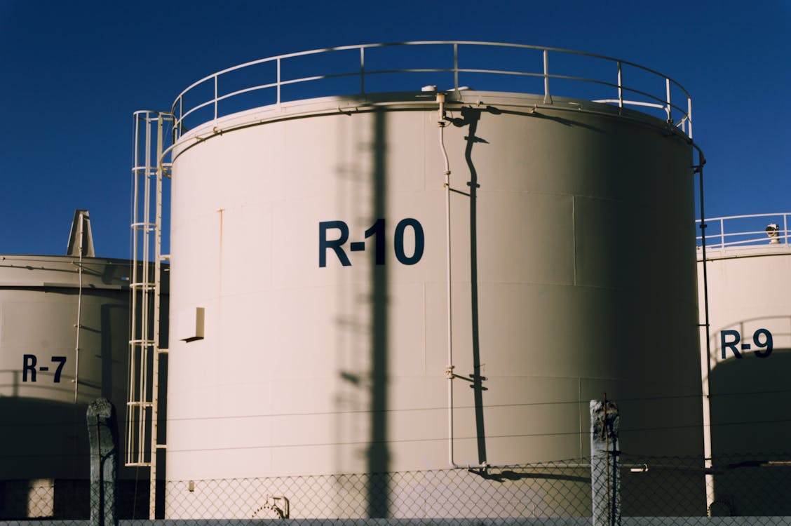 Free Large industrial storage tanks under blue skies, highlighting metal structures. Stock Photo