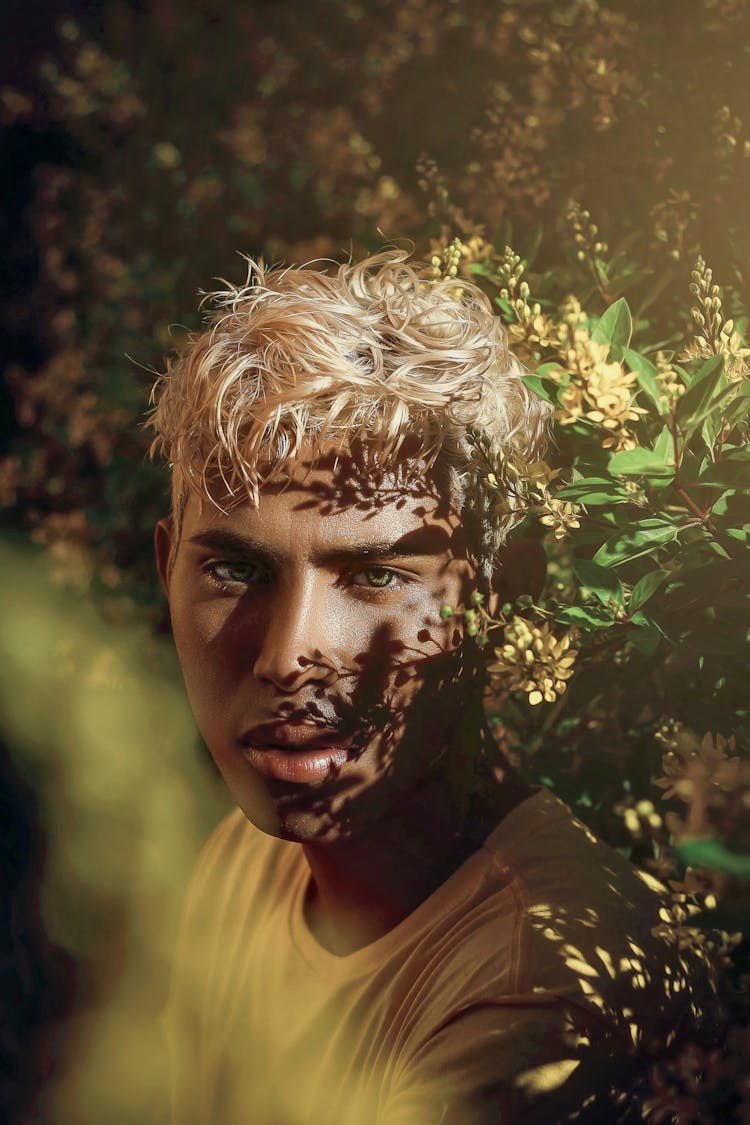 Portrait Of A Young Blonde Man Sitting In A Park