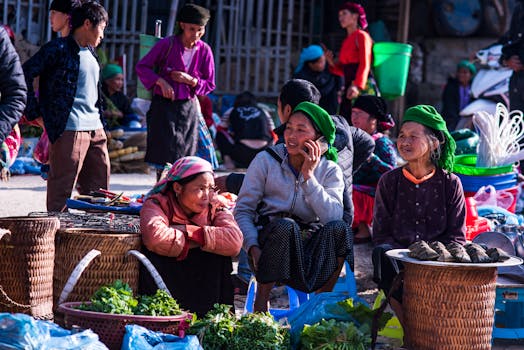 Lively street market with Asian women vendors selling produce and engaging in conversation.