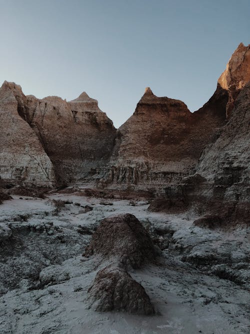 Severe scenery of rough formation with rocky uneven cliffs around barren terrain against cloudless blue sky